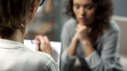 Young depressed woman talking to lady psychologist during session, mental health © motortion