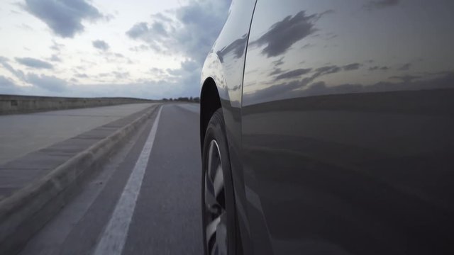 A car driving slowly along the road before sunset
