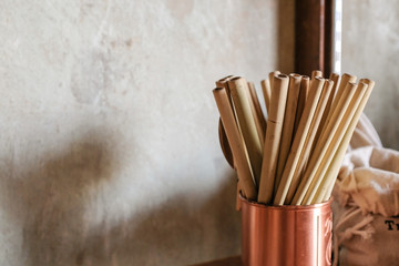 Close up of natural color bamboo straws in rose gold bronze cup  with loft concrete background