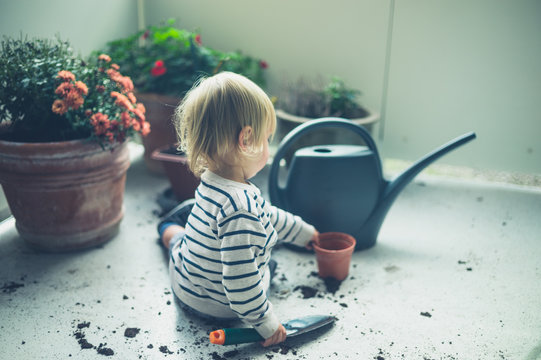 Toddler playing with dirt and watering can