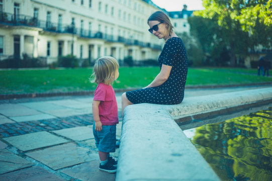 Young woman playing with toddler by fountain