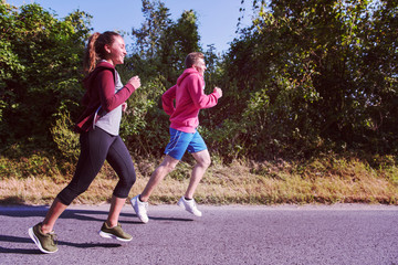 young couple jogging along a country road