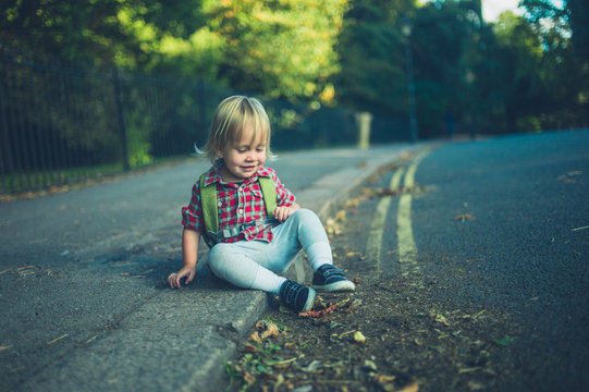 Toddler sitting on the sidewalk in park