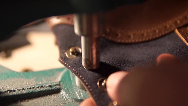 tailor sets rivets on clothing products using tongs, leather production