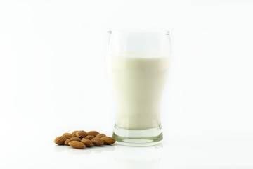 Almond milk in glass with almonds seed on white background