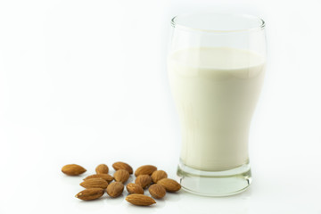 Almond milk in glass with almonds seed on white background
