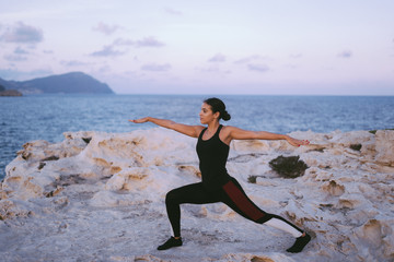Fototapeta na wymiar Portrait of gorgeous young woman practicing yoga on the beach