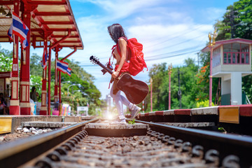 woman traveler holding guitar walking across railway station from side to another side, traveling woman, backpacker walking, find hurry destination