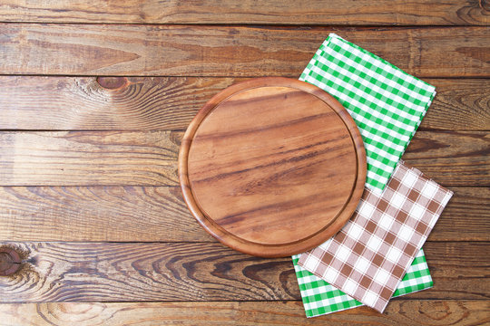 Brown old vintage wooden table with framed checkered tablecloth and pizza cutting board.Thanksgiving day and Cristmas table concept. Top view and copy space. Selective focus