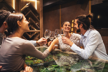 Happy couples toasting with wine at a restaurant