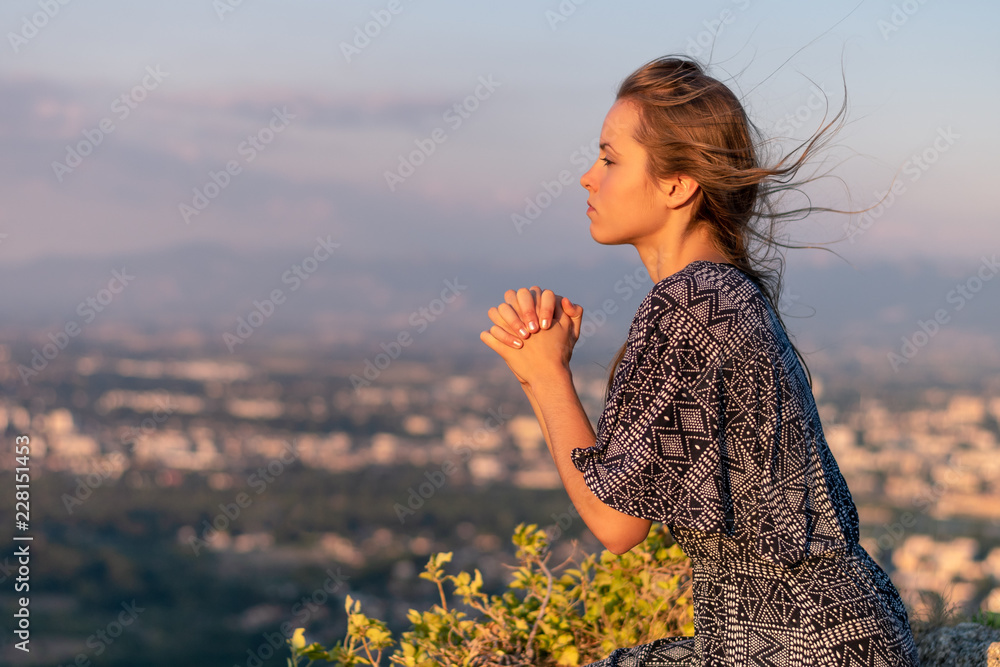 Wall mural christian worship and praise. a young woman is praying in the evening. - Wall murals