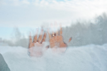 .male and female hand with wedding rings on frozen iced glass, winter wedding