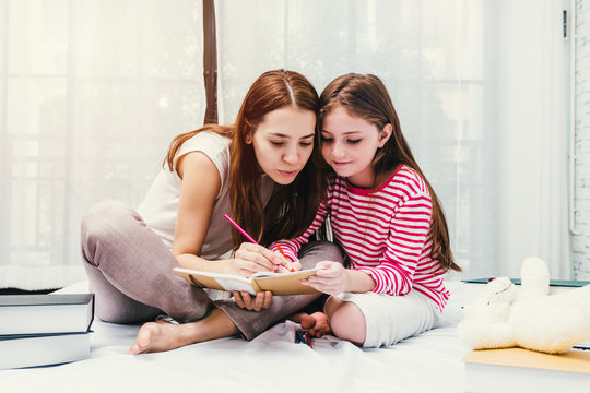 Family Happy Mother and daughter drawing with colorful pencils on book in bedroom