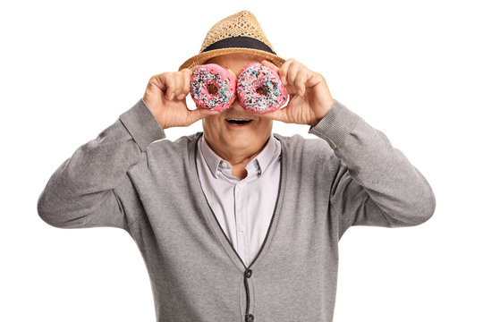 Mature man holding donuts in front of his eyes