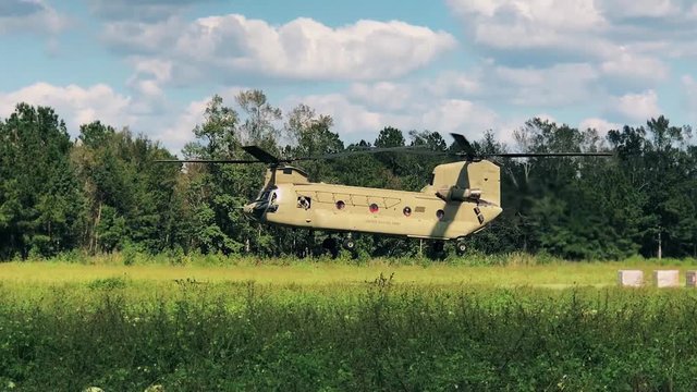 A Chinook Helicopter takes off from a grassy field.