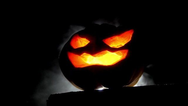 Big scary Halloween pumpkin with luminous eyes and smoke with back light