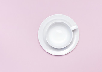 Obraz na płótnie Canvas Flat lay top view White empty ceramic cup on a saucer on pink background. Concept morning breakfast, drink coffee or tea. Background utensils, kitchen items. Minimalistic background