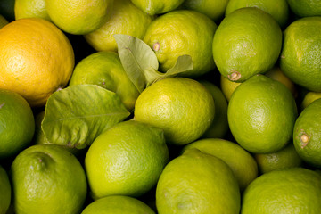Pile of fresh green yellow limes at market for sale - top view