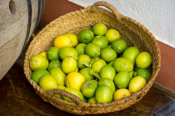Pile of fresh green yellow limes at market for sale in wooden basket