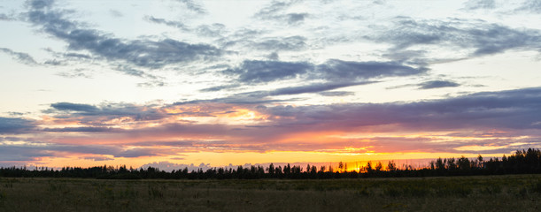 Panorama of sunset over the field in summer