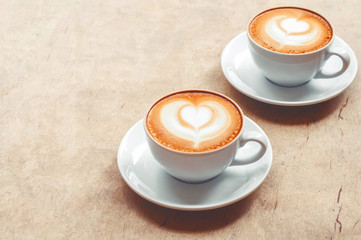 Two cup of cappuccino with latte art on wooden background. Hot coffee on table. Top view, flat lay copy space for text. Beautiful foam, copy space.