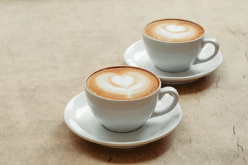 Two cup of cappuccino with latte art on wooden background. Hot coffee on table. Top view, flat lay copy space for text. Beautiful foam, copy space.