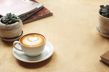 Cup of cappuccino with latte art on wooden background with plant. Hot coffee with flower on table. Top view, flat lay copy space for text. Beautiful foam, top view, copy space.
