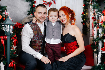 A young family sitting on the floor near a Christmas tree