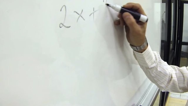 Hand Writing Math Formula for Elementary School on a Whiteboard / Man solving linear equations with one unknown using black marker pen on whiteboard