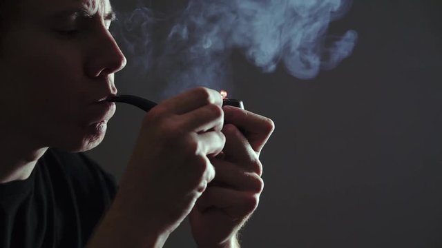 man lights Smoking pipe