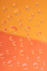 close-up view of transparent calm water drops on orange background
