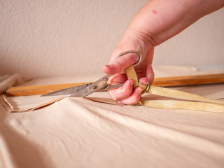 Hand with scissors cutting cloth. Clothes designer