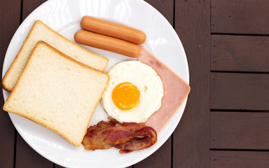 Simple breakfast. Toast bread, fried egg, sausage, ham and bacon.