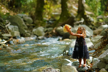 little girl bathes a doll in a mountain river