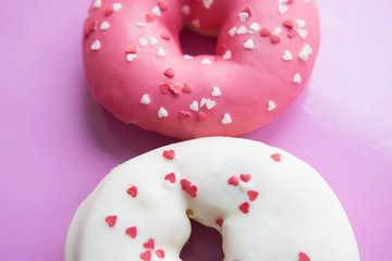 Pink and white donuts with sprinkles and different fillings. 