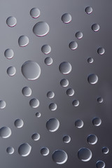 close-up view of transparent clear droplets on grey background