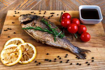 Fresh dorado grill with lemon and cherry tomatoes on a wooden tray. For restaurant menu or recipe