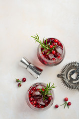 Cold refreshing drink with cranberries and rosemary on a white concrete background. Top view, copy space.