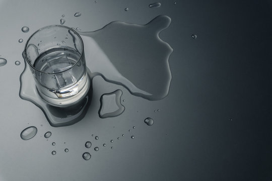 close up of a glass of water with ice cubes on the wet table
