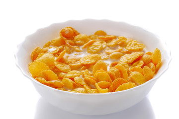 closeup of corn flakes with milk in a white bowl, isolated on white background