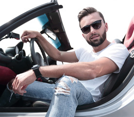 close up.stylish young man sitting in a luxury car