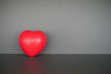 Fototapeta na wymiar Red heart shape ball infront of gray background.