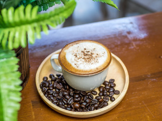 Cup of cappuccino coffee on wooden table in cafe.