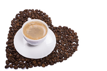 Isolated cup of coffee on beans scattered in heart shape