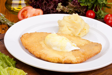 Chicken schnitzel with mashed potatoes on white plate. Close up