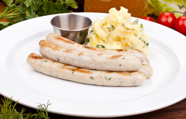 Munich sausages with potato salad on white plate. Close up