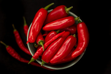 Red chili peppers in a plate on a dark background, top view