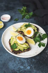 Healthy toast with avocado and egg. Whole grain rye toast on white plate