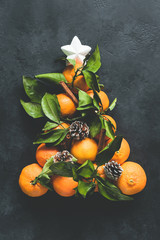 Christmas Tree made of tangerines and pine cones on black concrete background. Top view. Christmas and New Year Holidays concept