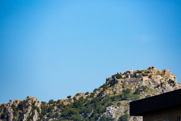 Fototapeta na wymiar The ruins of Haj - Nehaj fortress, Sutomore, Montenegro, as seen below from the town. Springtime clear blue sky landscape view
